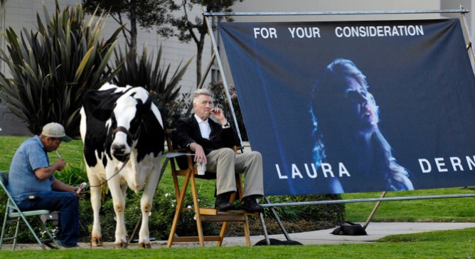 "Inland Empire" writer/director David Lynch (R) is joined by a live cow and its handler Mike Fanning as he promotes the film's star Laura Dern for movie awards season at the intersection of Hollywood Blvd. and La Brea Ave. in Los Angeles, December 13, 2006. Lynch said he was performing the stunt "to promote Laura Dern for every award because I believe she gave the best performance of the year and one that will live on in time." REUTERS/Chris Pizzello (UNITED STATES)